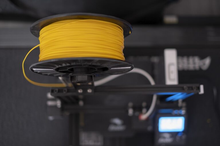 Yellow PLA filament spool mounted on 3D printer for Bambu A1 Mini printing