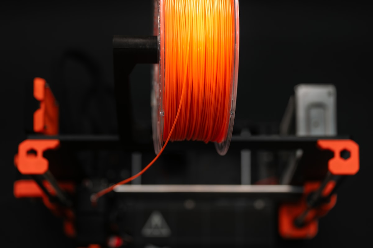 Bambu PETG HF vs Polymaker PETG - orange PETG filament spool on 3D printer