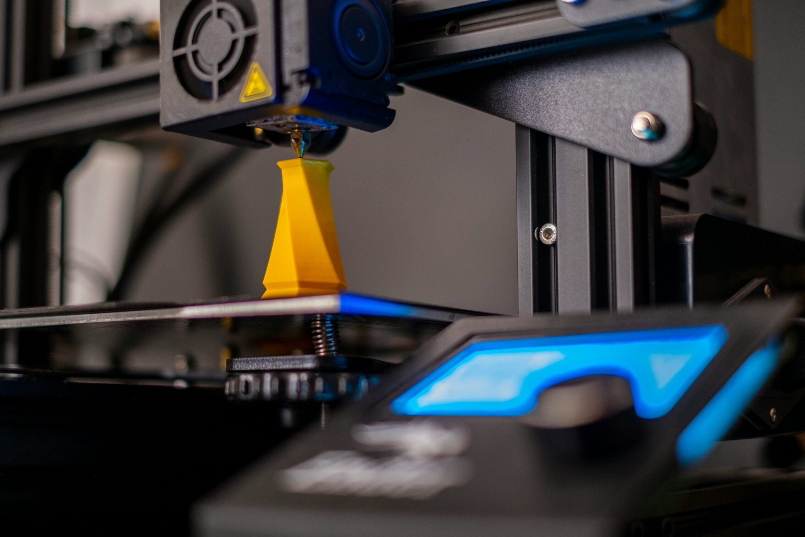 3D printer printing a yellow PETG part with blue LED lighting — best PETG filament for Bambu Lab guide