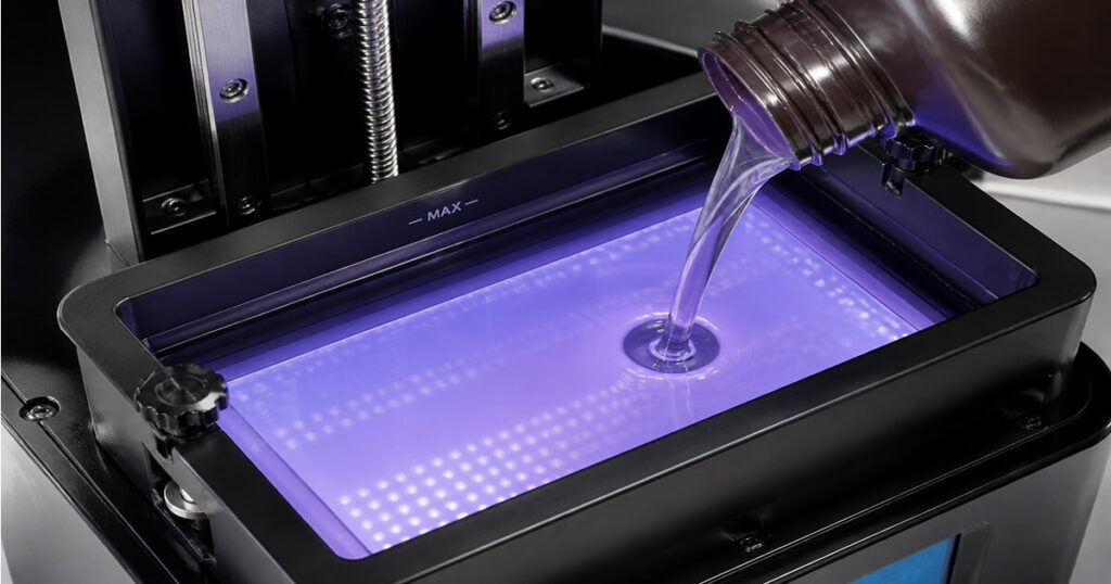 Liquid photopolymer resin being poured into an MSLA 3D printer resin vat for fast exposure printing of detailed models.