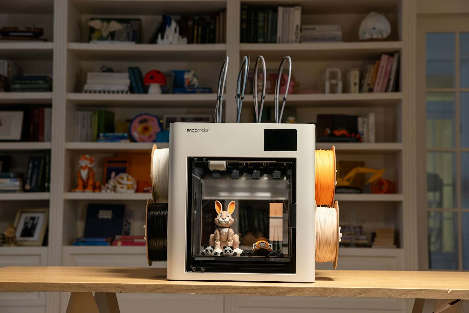 Compact 3D printer producing a small PLA figure on a textured PEI plate