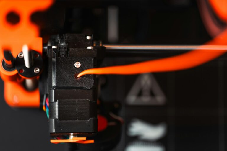 PETG vs ABS — close-up of a 3D printer nozzle extruding filament
