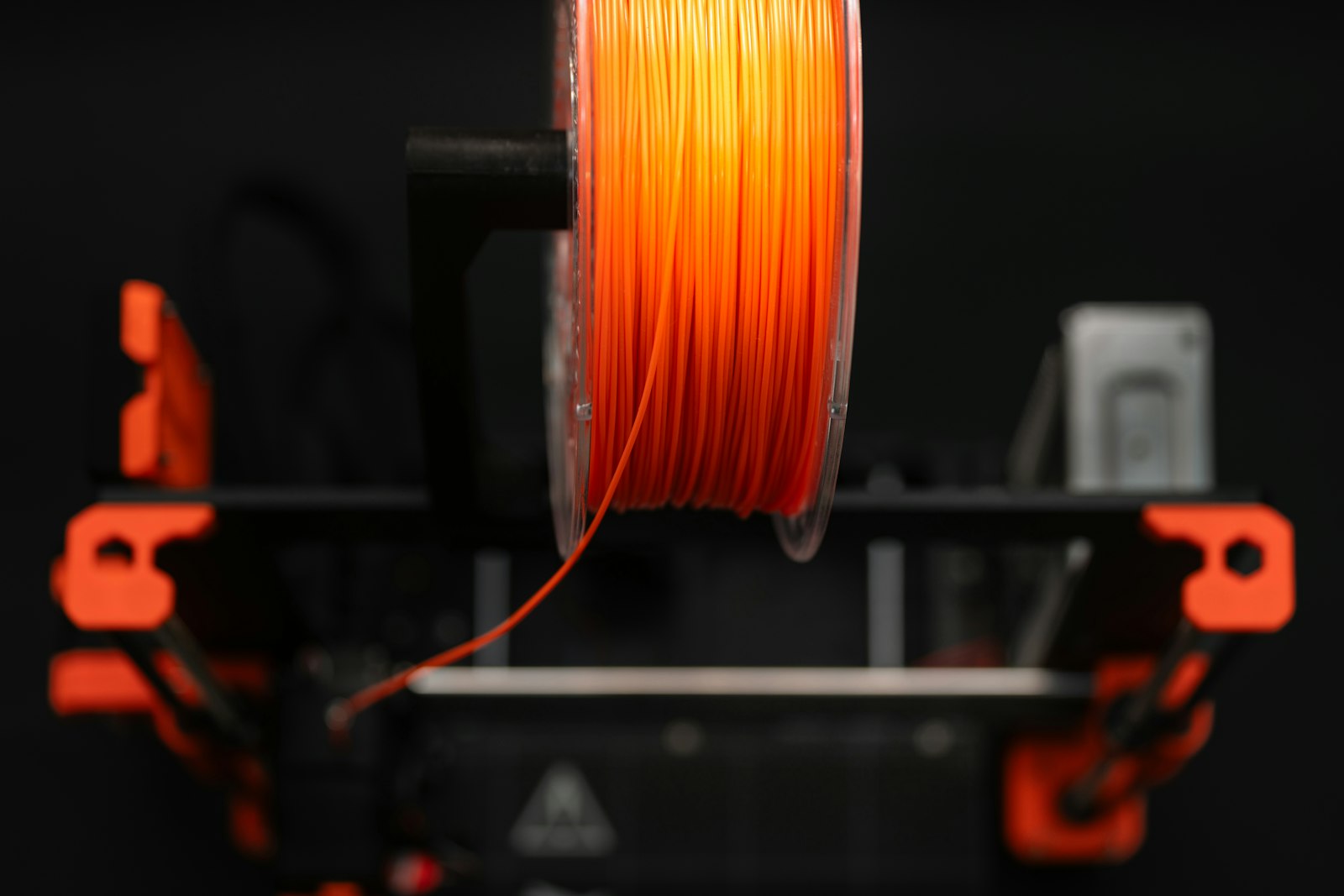 PLA stringing prevention — orange PLA filament spool mounted on a 3D printer